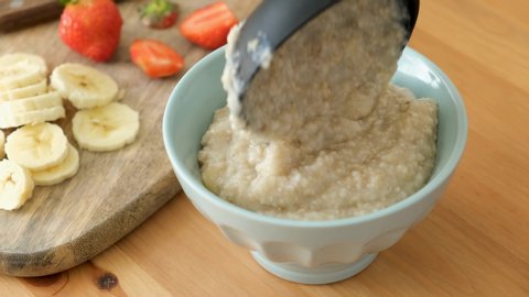 Serving oatmeal porridge in bowl. 4k footage of preparing healthy breakfast