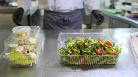 Food delivery in the restaurant. The chef prepares food in the restaurant and packs it. Panna cotta and vegetable salad in a plastic disposable containers