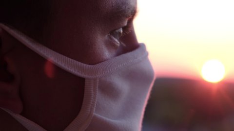 Pandemic portrait of a young guy in a mask at sunset, close-up