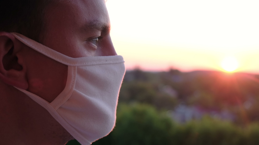Young guy taking off protective mask at sunset, closeup. The victory over the coronavirus pandemic Royalty-Free Stock Footage #1052828663