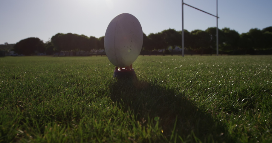 Side view low section of a teenage Caucasian male rugby player wearing a red and white team strip, kicking a rugby ball on a playing field in slow motion Royalty-Free Stock Footage #1052828882
