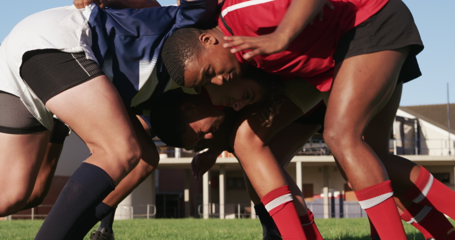 Side view close up of two teenage multi-ethnic male teams of rugby players wearing their team strips, in action forming a scrum during a rugby match on a playing field in slow motion Royalty-Free Stock Footage #1052829152