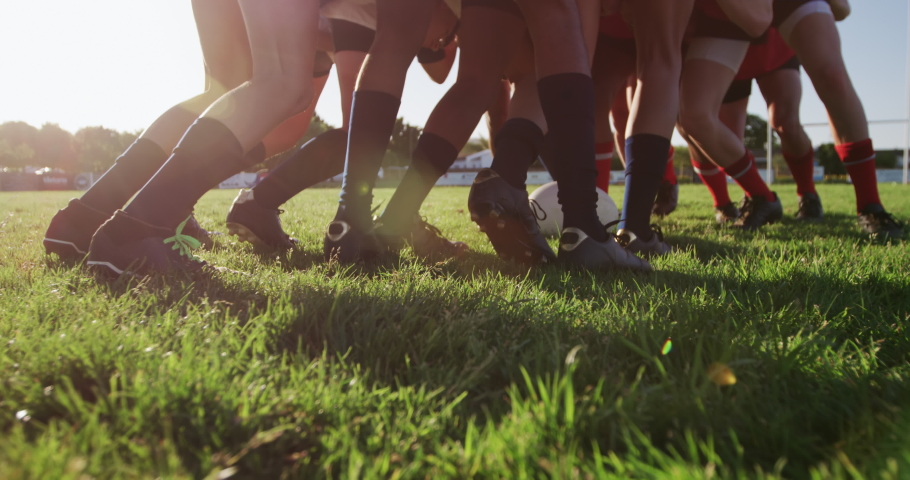 Low angle side view of two teenage multi-ethnic male teams of rugby players wearing their team strips, in action forming a scrum during a rugby match on a playing field in slow motion Royalty-Free Stock Footage #1052829422
