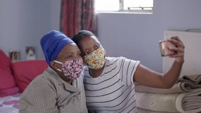 Black South African mother and daughter take selfies in their home wearing their covid-19 coronavirus protective masks.  - Powered by Shutterstock - Get 15% off with code: PIKWIZARD15