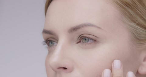 Macro Close up of Beautiful healthy woman touching smooth skin on face in slow motion for beauty skincare concept on a grey background Shot in 6K on RED EPIC DRAGON