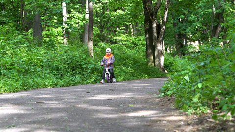 little boy rides a bicycle in the park