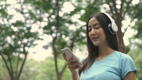 Holiday concept. The girl is listening to the music in the park. 4k Resolution.