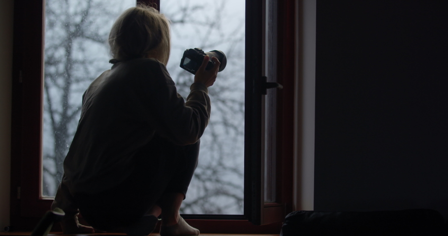 A beautiful girl getting in place on a window to photograph the first snowfall of the year