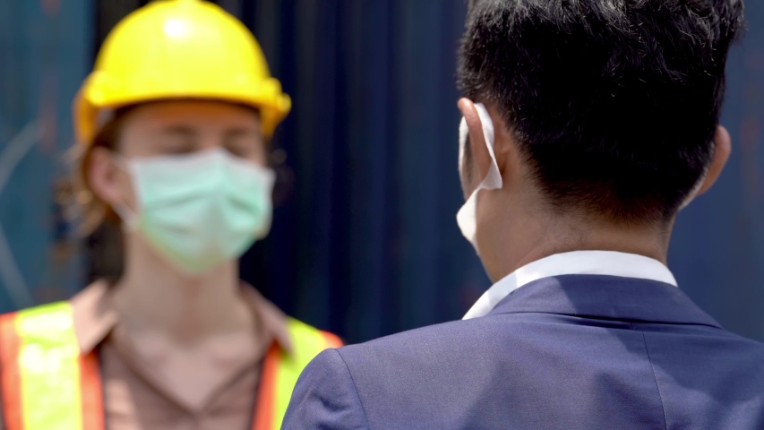 factory worker in mask face and using measures temperature check body temperature at workplaces with a thermometer during a virus pandemic COVID-19. And man worker going pass inside factory. Royalty-Free Stock Footage #1052837387