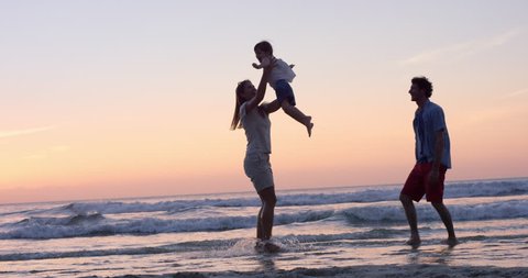 Mother swinging little girl around Happy family on the beach holding hands sat sunset on vacation slow motion RED DRAGON