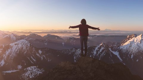 Fantasy Adventure Composite with a Girl on top of a Rock Cliff with Beautiful Canadian Mountain Nature Landscape in Background during Sunset or Sunrise. 2.5D Parallax