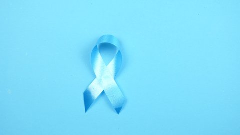Hold hands light blue ribbon on sky blue color background.
National Child Abuse Prevention Month, 
Men with localised prostate cancer are risk stratified 
top view.  