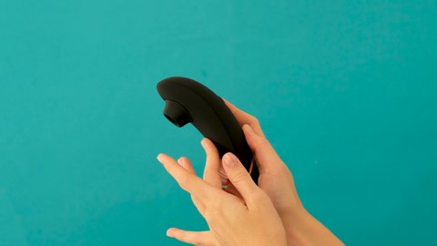 Woman holds vacuum clitoris stimulator isolated on blue background