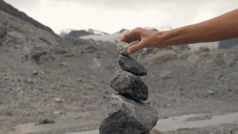 Detail of person stacking rocks by the river near glacier, shot in Graubünden Canton, Switzerland. People life balance concept