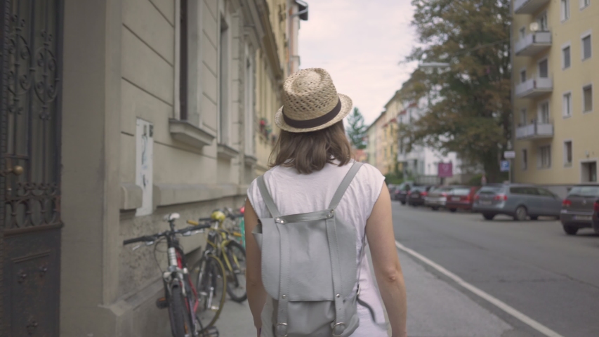 Young woman wearing cute straw hat walking down the street looking around