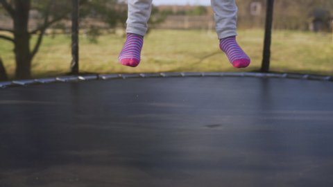 Little girl jumping on the trampoline in the back yard. Teenager bouncing on the trampoline

