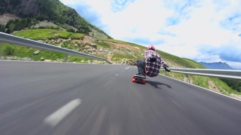 downhill road in mountain landscape professional skater skating longboard fast in first person pov