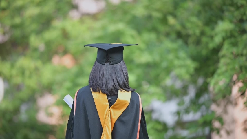 An Asian female graduate who graduates from the university smiles and congratulates her graduation on the university. Royalty-Free Stock Footage #1052856644