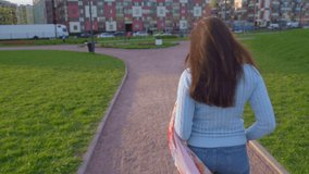  Sunny video of female walking in Park fresh air at sunset. Middle-aged brunette girl, wind blows long dark hair, Life