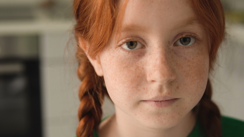 Shy red haired girl 7 years old looking at camera, shaming. School kid portrait Royalty-Free Stock Footage #1052858813