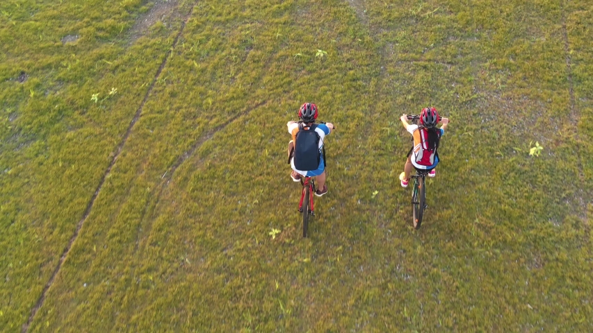 Footage B Roll 4k. Aerial view Drone tracking young People riding a bikes on the meadow, aerial view. Love Couple cycling on green lawn together, aerial drone view. Healthy lifestyle concept. | Shutterstock HD Video #1052862005
