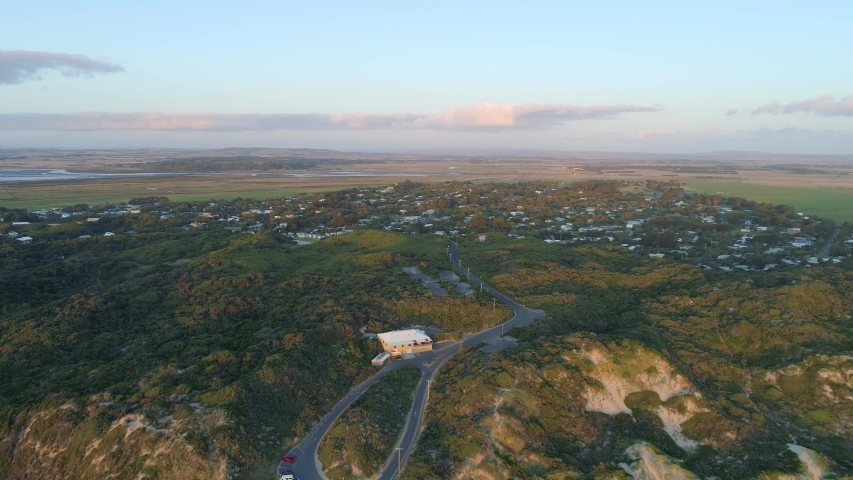 Backward flight away from Venus Bay beach ocean coastline into the ocean at sunset. Victoria, Australia
