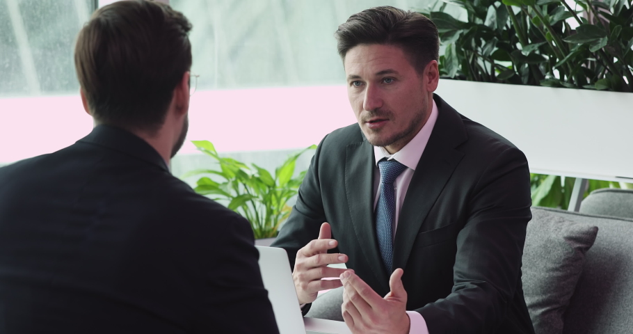 40s focused confident human resources manager in formal wear holding job interview with skilled young male candidate. Two businessman discussing project ideas at negotiations meeting in modern office. Royalty-Free Stock Footage #1052867000
