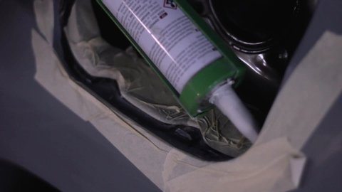 Man smearing hermetization paste on car body during repair service