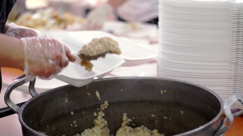 close-up, female Volunteer puts porridge into lunchboxes from large pan. Charity hot meals for poor and homeless people. Free food delivery. donating aid,