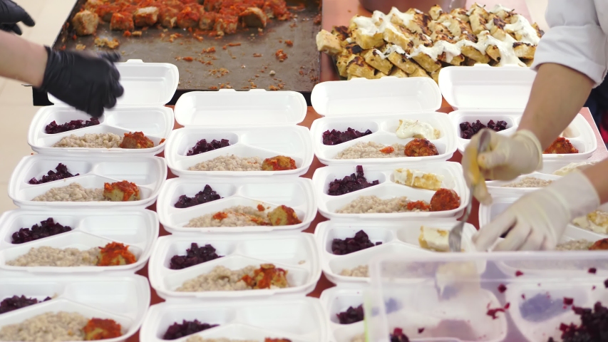 close-up, Volunteers pack free hot meals in lunchboxes, for poor people during lock down of covid19. food delivery. Charity project, donating aid, Royalty-Free Stock Footage #1052876234