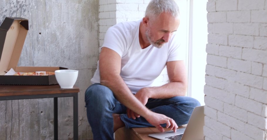 An adult man works at home on self-isolation, makes online orders, uses a coputer