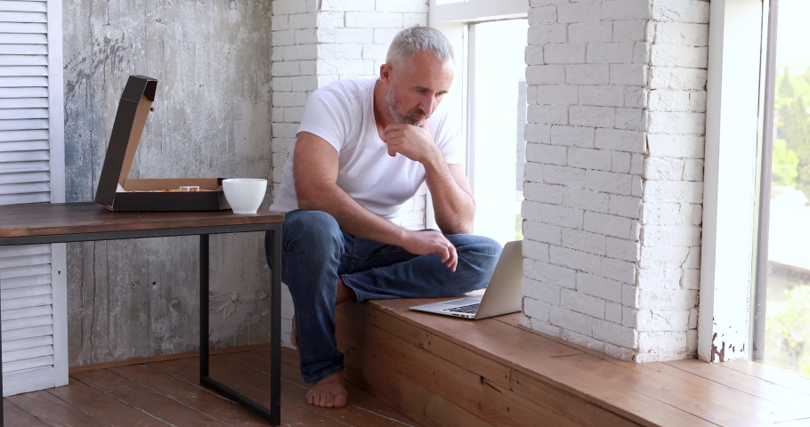 An adult man works at home on self-isolation, makes online orders, uses a coputer