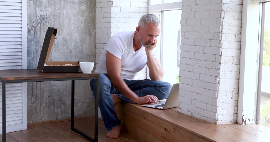 An adult man works at home on self-isolation, makes online orders, uses a coputer