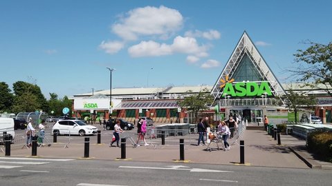 Leeds UK, 21st May 2020: People in the UK queuing following social distancing rules at the Pudsey Asda supermarket, standing two metres apart due to social distancing on a hot sunny summers day.