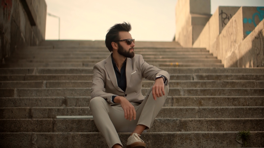 
Businessman Relaxing And Sitting On Steps.Lonely Handsome Confident Man In Suit Thinking Outdoors.Successful Businessman In Suit Resting On Stairs.Attractive Man In Sunglasses Enjoying After Work Day | Shutterstock HD Video #1052887451
