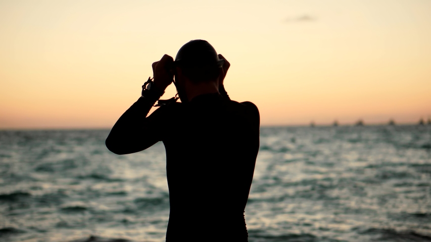 Swimmer Silhouette In Ocean. Professional Triathlete Preparing To Swimming Workout On Sea. Triathlete Preparing To Triathlon Swim.Athlete Swimmer Wearing Cup And Goggles. Sport Recreation Competition  Royalty-Free Stock Footage #1052887799