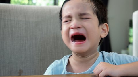 Asian little boy crying at dining table.Sad or depress kid.
