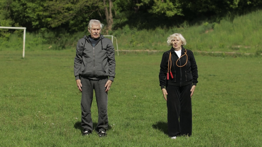 Active senior elderly couple 80 years old. Caucasian man and woman do morning stretching physical exercises in sport playground background. Active fitness family leisure. Healthy lifestyle