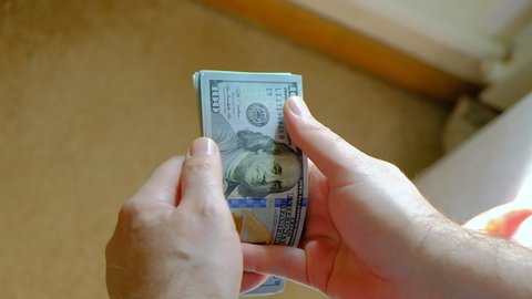 Man counts hundred-dollar bills. Close-up of men's hands counting money in cash