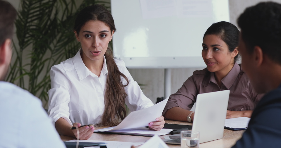 Beautiful millennial businesswoman holding paper marketing research reports, discussing growth strategy with diverse teammates. Motivated employees brainstorming on project, sharing ideas in office. | Shutterstock HD Video #1052897486