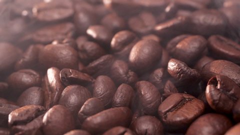 Coffee beans are falling, slow motion. Coffee with steam. Coffee beans close-up with smoke.
