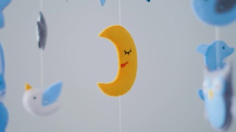 baby mobile with different animals hanging over the crib of a newborn baby in the bedroom on a white background