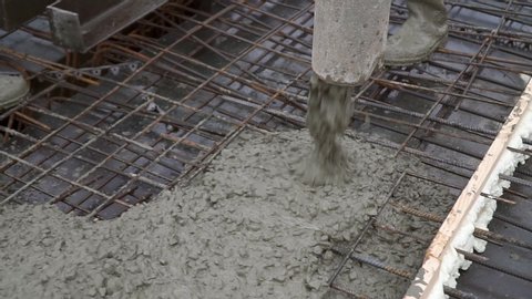 Pouring concrete mixture with a pump pipe to the reinforcing mesh. Pouring concrete floors of buildings at a construction site