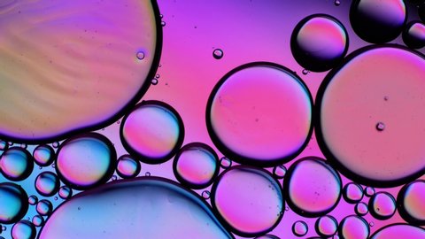 Top view movement of oil bubbles. Oil surface multicolored background. Fantastic structure of colorful bubbles. Colorful artistic image of oil drop floating on the water.