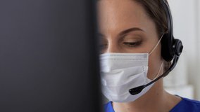 medicine, technology and healthcare concept - female doctor or nurse wearing face protective medical mask for protection from virus disease with headset and computer working at hospital