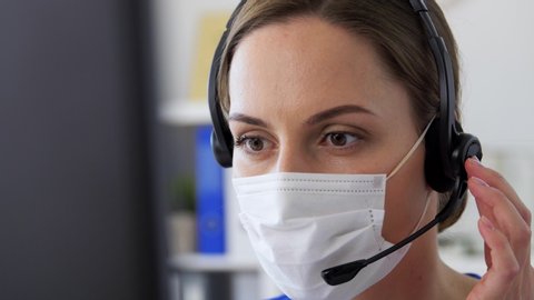 medicine, technology and healthcare concept - female doctor or nurse wearing face protective medical mask for protection from virus disease with headset and computer working at hospital