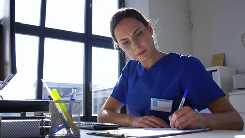 medicine, technology and healthcare concept - female doctor or nurse with computer and medical report working at hospital