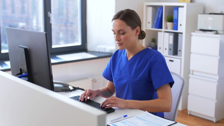 medicine, technology and healthcare concept - female doctor or nurse with computer and medical report working at hospital Royalty-Free Stock Footage #1052912669