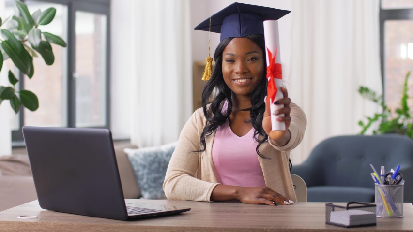 e-learning, education and people concept - happy smiling african american female graduate student with laptop computer and diploma at home Royalty-Free Stock Footage #1052912723