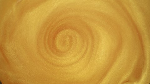 A swirl of gold paint in dissolved water. Circular mixing of gold powder